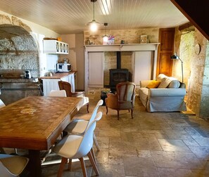 Un intérieur rustique avec une cheminée en pierre, une table à manger en bois et un coin salon confortable.