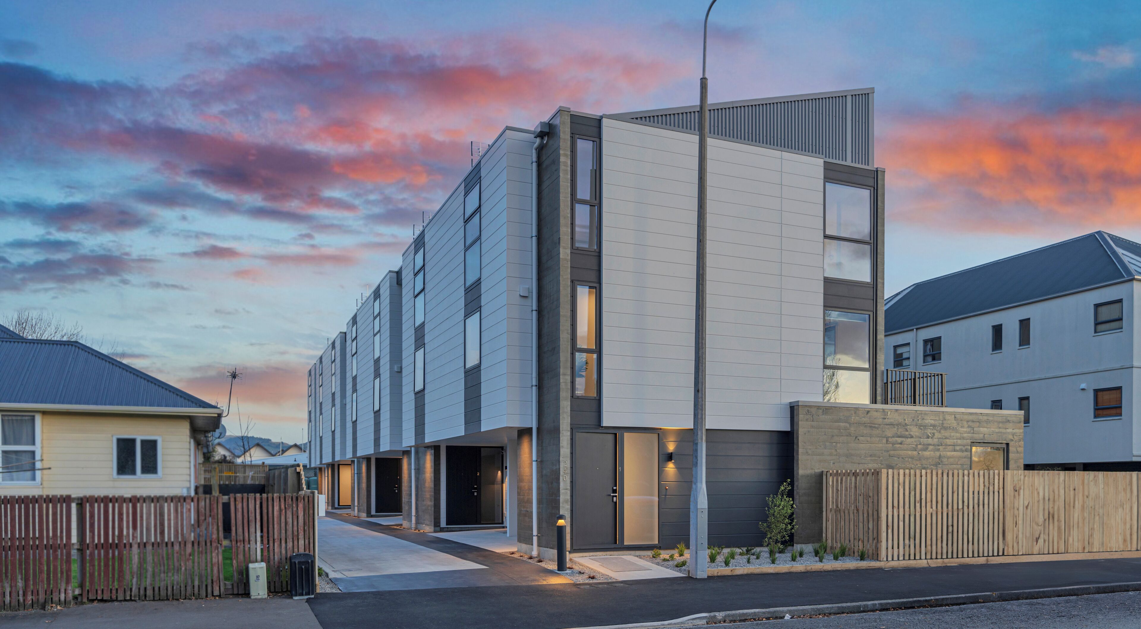 Un immeuble moderne à plusieurs étages, doté d’un toit plat, de grandes fenêtres et d’une entrée sécurisée par un portail.