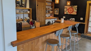 A modern kitchen with wooden countertops, a built-in washing machine, and bar stools.