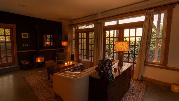 A cozy living room with a fireplace, comfortable seating, and large windows with curtains.