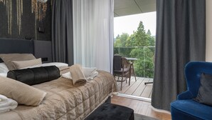 A bedroom with a bed, a chair, and a balcony with a view of trees. - Holiday Studio With Balcony, Indoor Pool, Sauna (Polanica-Zdroj)