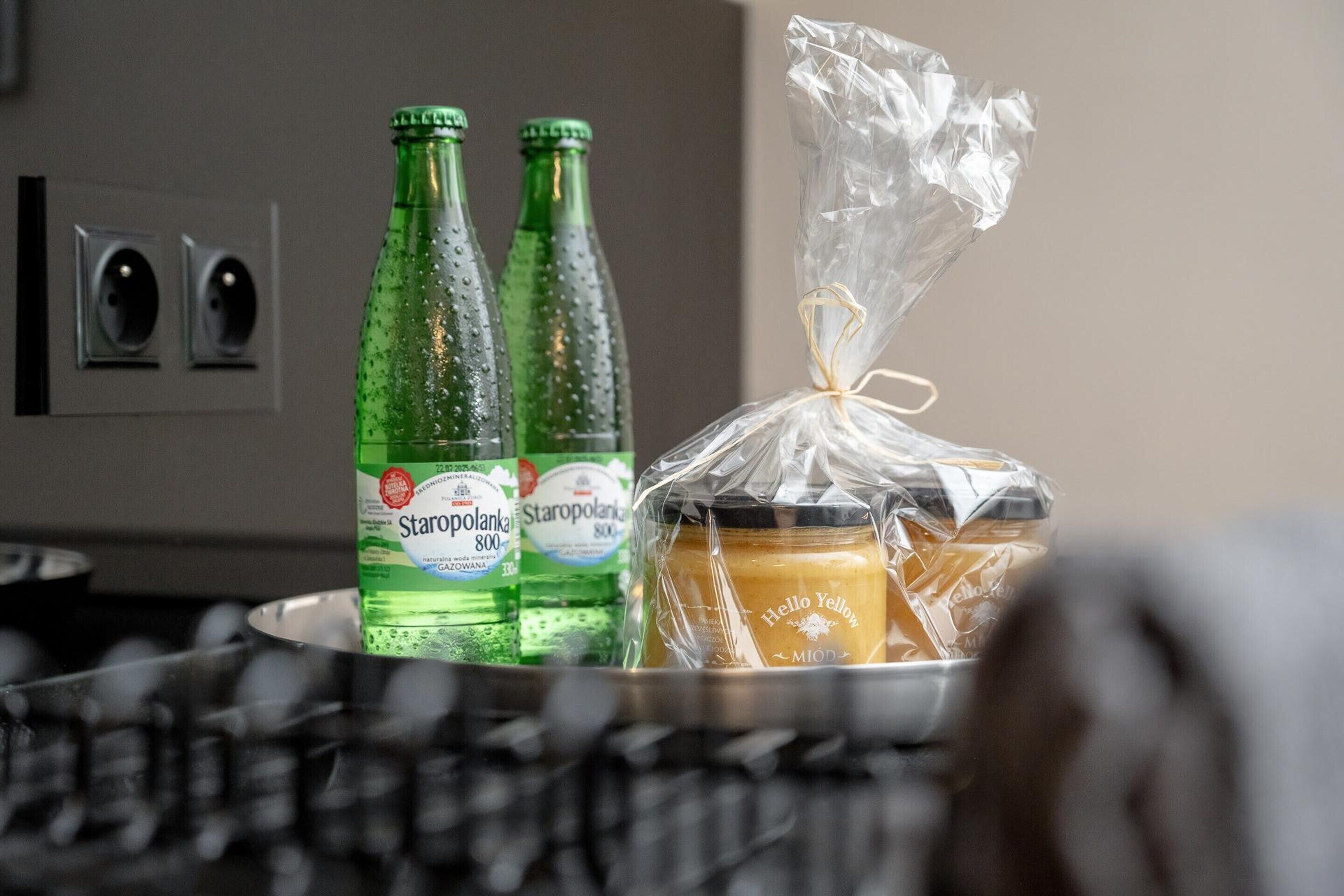 A kitchen counter with two Staropolska 800 bottles, a jar of Hello Yellow, and a plastic-wrapped item.