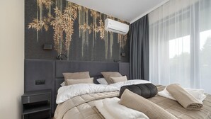 A modern hotel room with a large bed, a headboard with a vertical light, a bedside table, and a wall-mounted air conditioner. - Holiday Studio With Balcony, Indoor Pool, Sauna (Polanica-Zdroj)