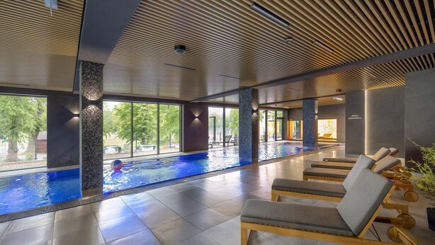 A modern indoor pool area with lounge chairs and a clear view of the outdoors. - Holiday Studio With Balcony, Indoor Pool, Sauna (Polanica-Zdroj)
