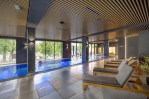 A modern indoor pool area with lounge chairs and a clear view of the outdoors. - Holiday Studio With Balcony, Indoor Pool, Sauna (Polanica-Zdroj)