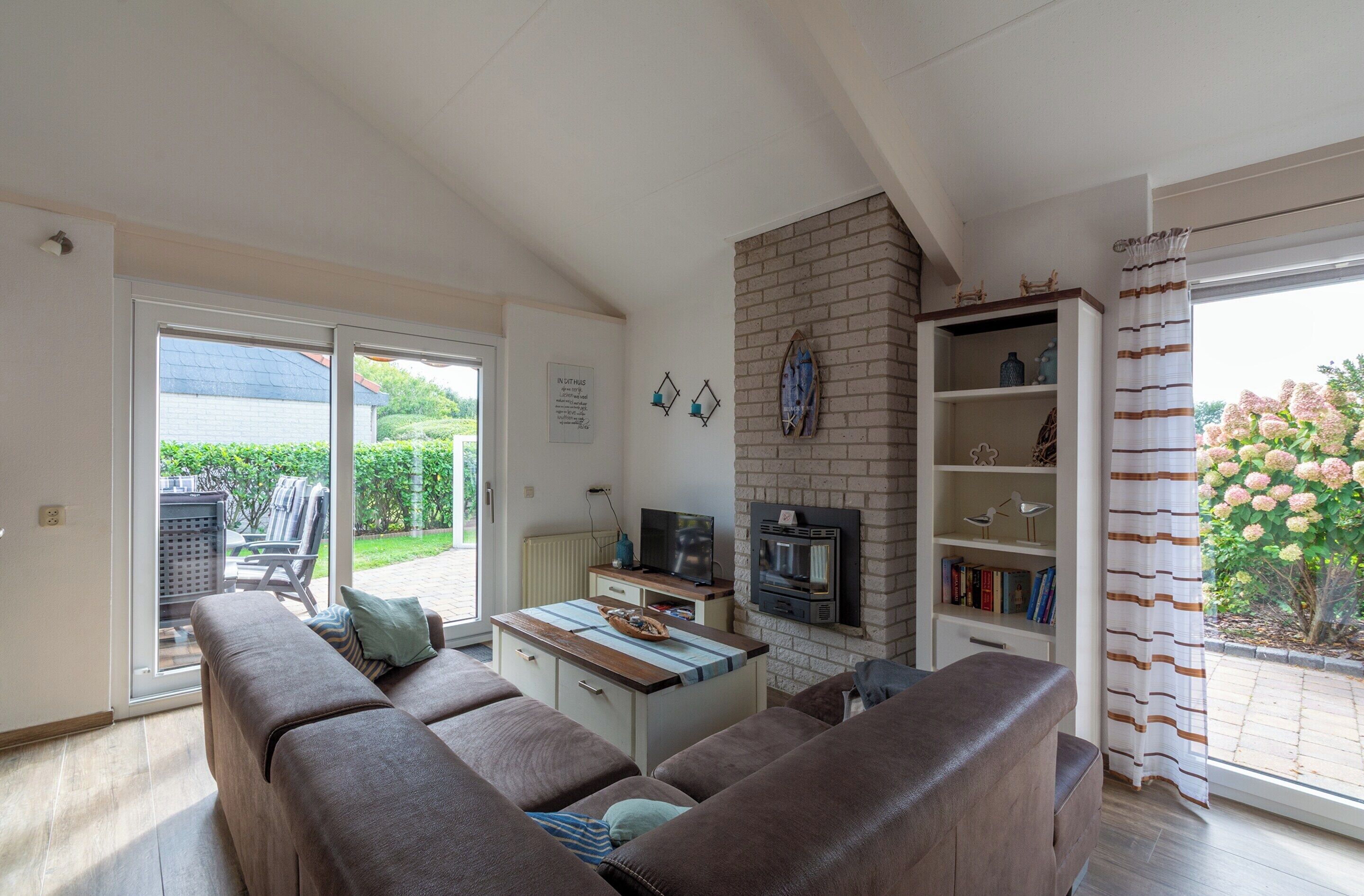 A cozy living room with a sofa, a small table, and a fireplace. There is a sliding glass door leading to an outdoor area.