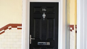 Uma porta preta com o número 31b, um puxador de metal e um pequeno objeto decorativo acima.