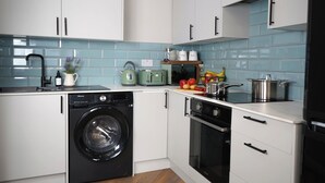 Uma cozinha compacta com máquina de lavar, forno e diversos eletrodomésticos.