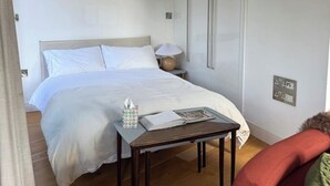 Une chambre à coucher avec un lit, une table de chevet, une lampe et une chaise.