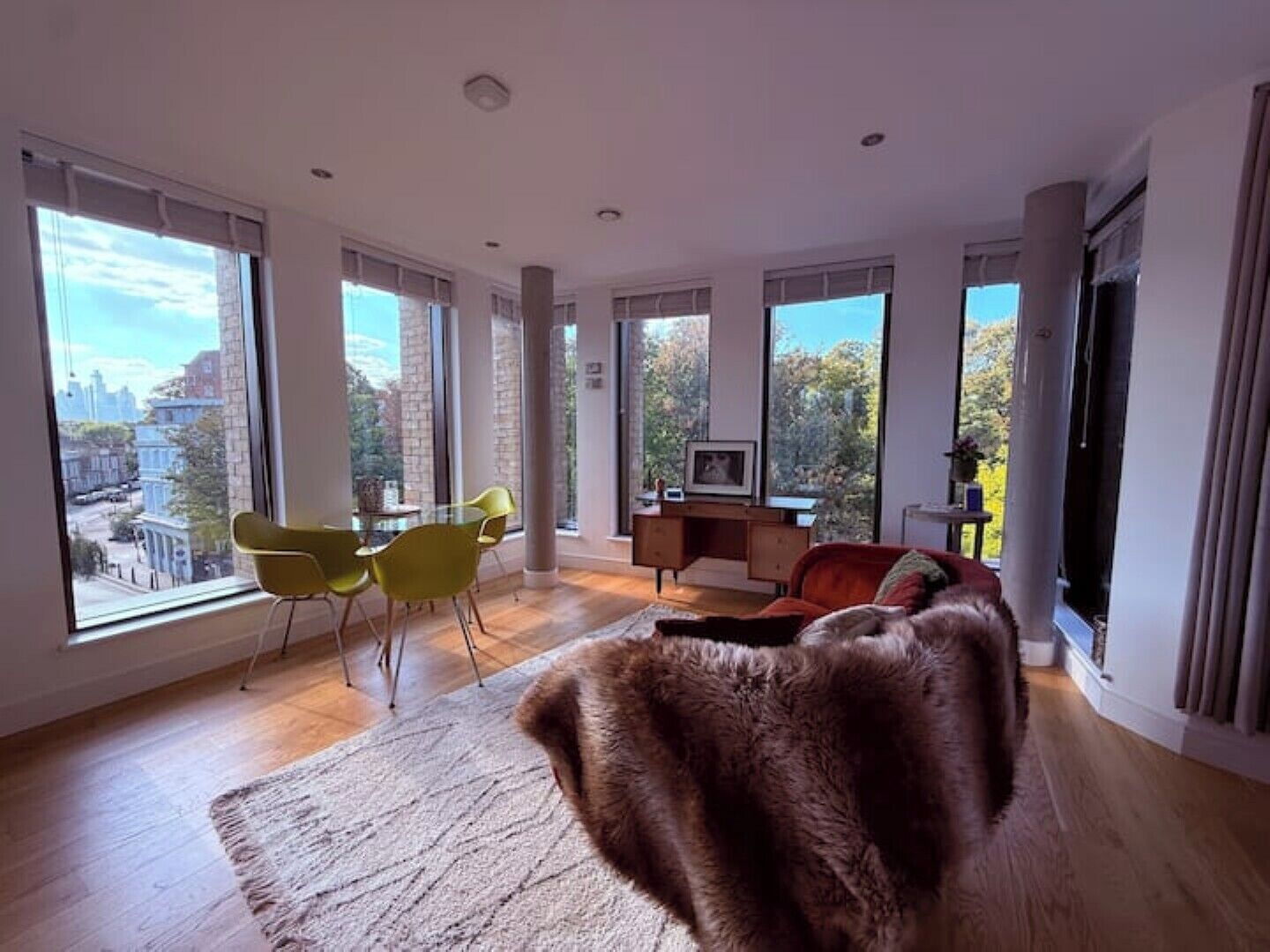 A spacious living room with large windows, a dining area, and a cozy seating area.