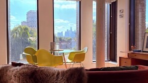 Un salon moderne avec une grande fenêtre, un canapé rouge et une table en verre entourée de chaises jaunes.