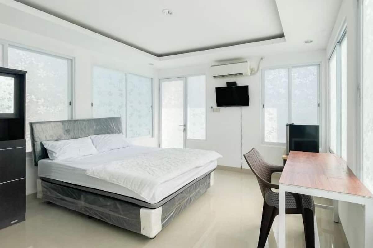 Quarto moderno com cama, escrivaninha e televisão.