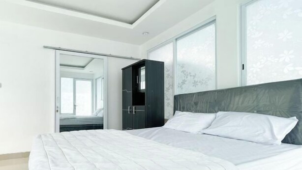 A bedroom with a bed, a wardrobe, and a sliding door leading to another room. - RedDoorz near Politeknik Pariwisata Nusa Dua Bali (Bali)