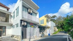 A two-story residential building with a gated entrance, a balcony, and a visible air conditioning unit. - RedDoorz near Politeknik Pariwisata Nusa Dua Bali (Bali)
