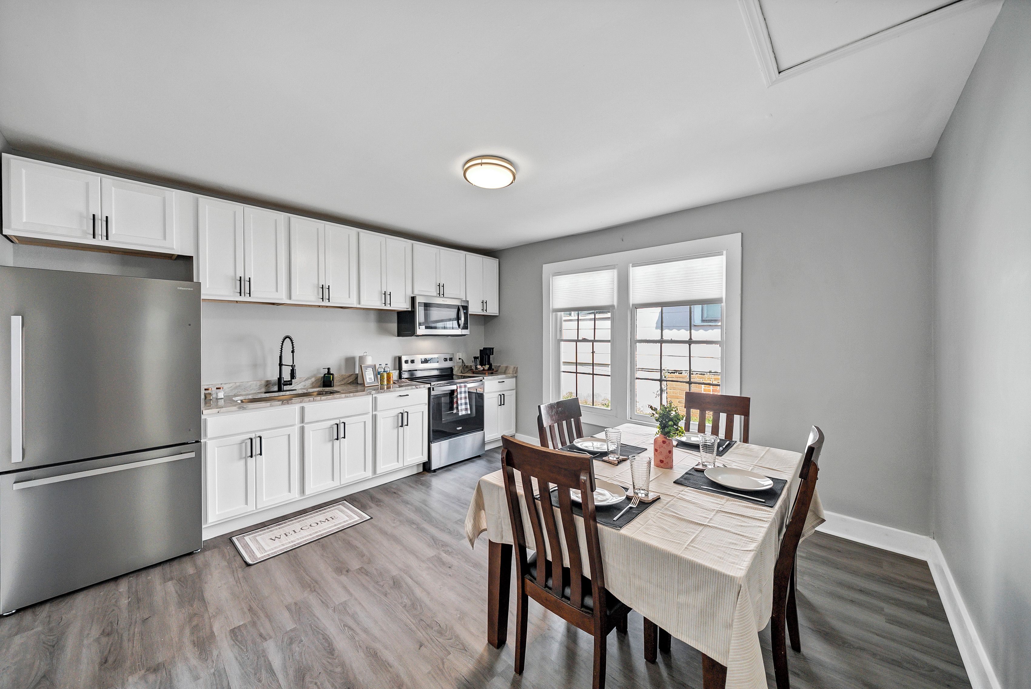 A modern kitchen with white cabinets, stainless steel appliances, and a dining area with a table set for two.