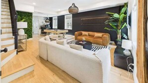 A modern living room with a sofa, coffee table, and a dining area with a table and chairs. - Luxe Chicago Retreat • Game Room, Deck + Fire Pit (Chicago)