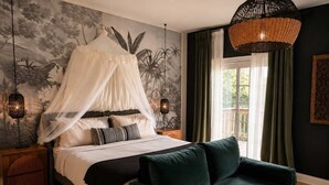 A bedroom with a bed, a green sofa, a canopy, a wall mural, a hanging light fixture, and a window with curtains. - Luxe Chicago Retreat • Game Room, Deck + Fire Pit (Chicago)