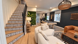 A staircase with patterned tiles, a billiards table, a sofa, and a coffee table in a modern living area.