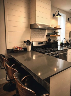 A modern kitchen with a central island, stainless steel appliances, and a built-in stove. - Desert Mirage Private Patio Desk Parking (Chicago)