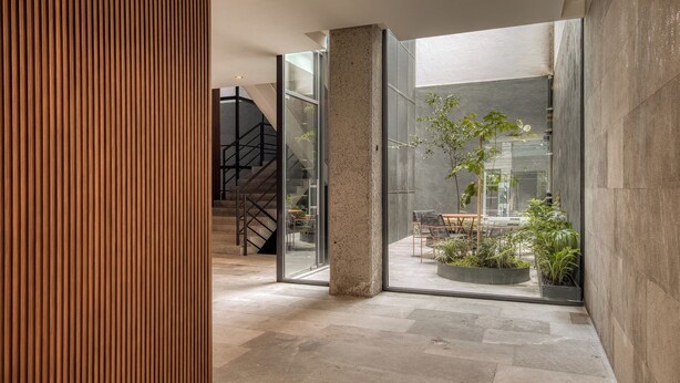 Een modern interieur met een trap, glazen wanden en een zithoek met planten.