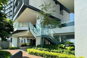 A multi-story building with a glass staircase connecting the levels, surrounded by greenery. - Continew Residence by Xuan and Partner (Kuala Lumpur)