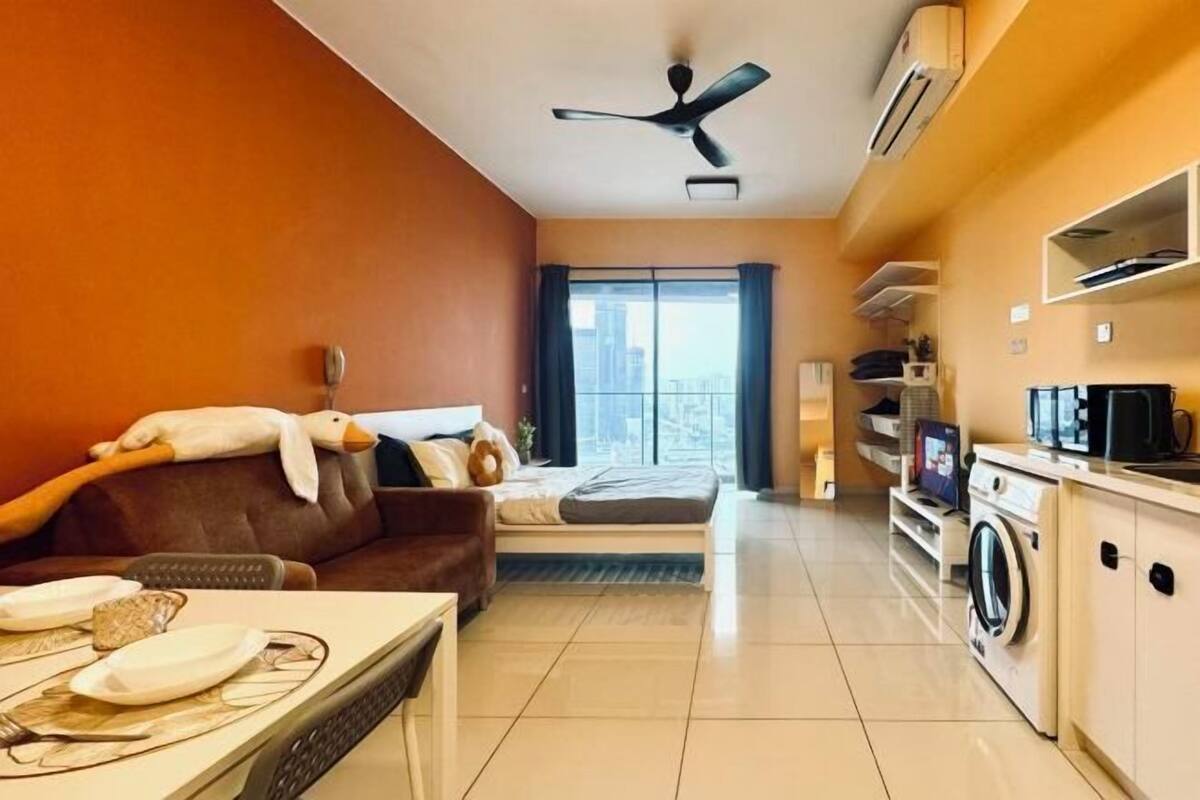Un espacio habitable compacto con sofá, comedor, cama, lavadora y ventilador de techo.