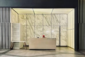 A reception area with a marble wall, a reception desk, and a glass display unit. - Continew Residence by Xuan and Partner (Kuala Lumpur)