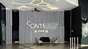 A modern interior with a black and white striped wall, a reception desk, and two chairs. - Continew Residence by Xuan and Partner (Kuala Lumpur)