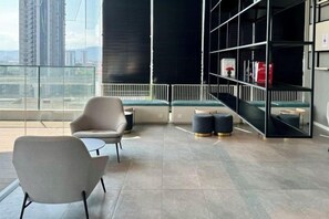A modern lounge area with a sofa, a small table, and a bookshelf. - Continew Residence by Xuan and Partner (Kuala Lumpur)
