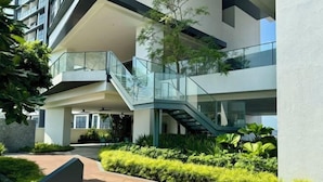 A modern building with a glass staircase connecting multiple floors, surrounded by greenery. - Continew Residence by Xuan and Partner (Kuala Lumpur)