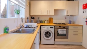Une cuisine compacte équipée d’un lave-linge, d’un four et d’un évier.