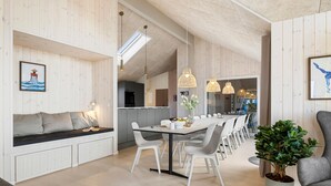 A modern kitchen with a dining area, wooden panel walls, and a large window.