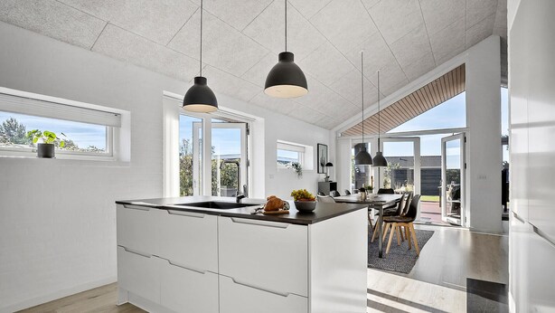 A modern kitchen with white cabinetry, a central island, and pendant lighting.