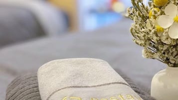 A neatly folded towel with a logo on a bed.
