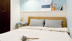 Ein Schlafzimmer mit hölzernem Kopfteil, einem Nachttisch mit Lampe und einem an der Wand hängenden Bild.
