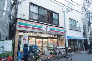 Una tienda de conveniencia 7-Eleven con entrada visible, una bicicleta estacionada afuera y una motocicleta en la calle.