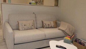 A living room with a sofa, a white coffee table, and a remote control on the table.
