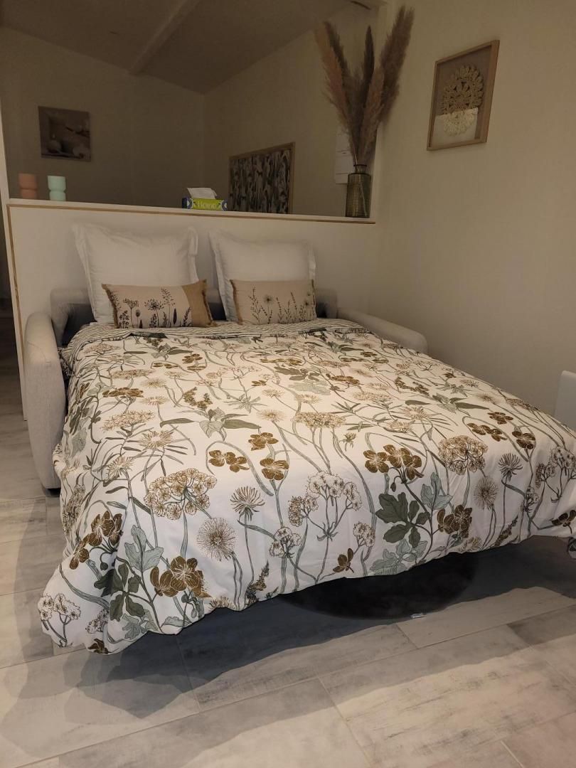 A bedroom with a bed, a nightstand, a chair, and a wall-mounted shelf with decorative items.