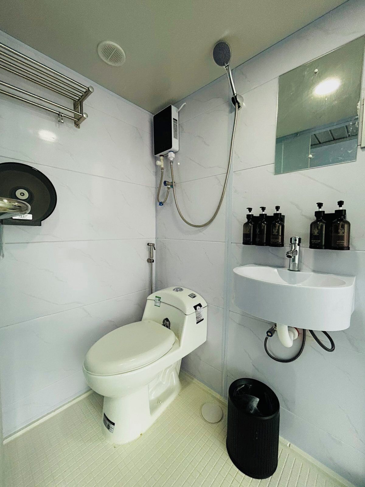 A modern bathroom with a toilet, a shower, a sink, and toiletries.