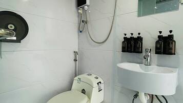 A modern bathroom with a toilet, a shower, a sink, and toiletries.