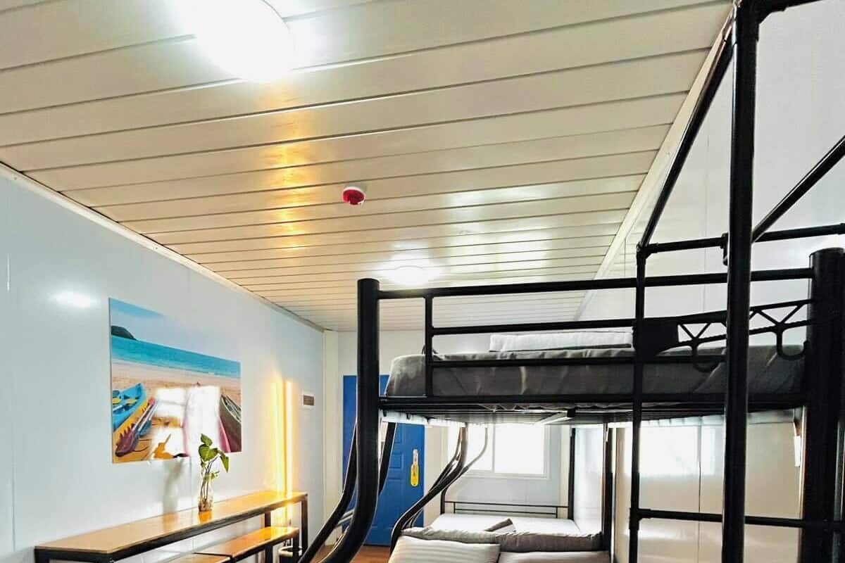 Een slaapkamer met een stapelbed, een houten bankje en een schilderij aan de muur.
