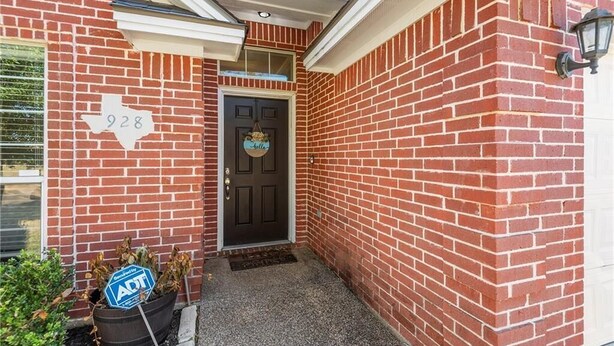 Une maison en briques avec une porte noire, une boîte aux lettres et une plaque portant le numéro « 928 » sur le mur.