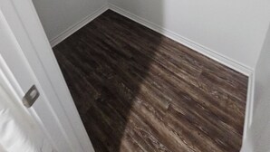 Une pièce dotée d’un plancher en bois, de murs blancs et d’un plafond blanc avec des poutres apparentes.