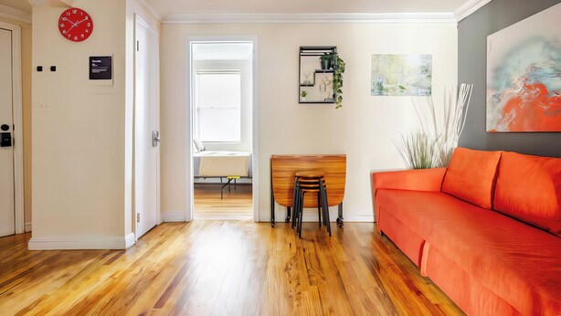 Ein modernes Wohnzimmer mit Holzböden, einem roten Sofa, einem Holztisch und einem Essbereich mit Stühlen.