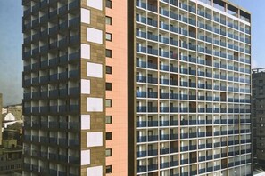 Un edificio de varios pisos con una cuadrícula de ventanas y balcones, probablemente un edificio residencial u hotel.