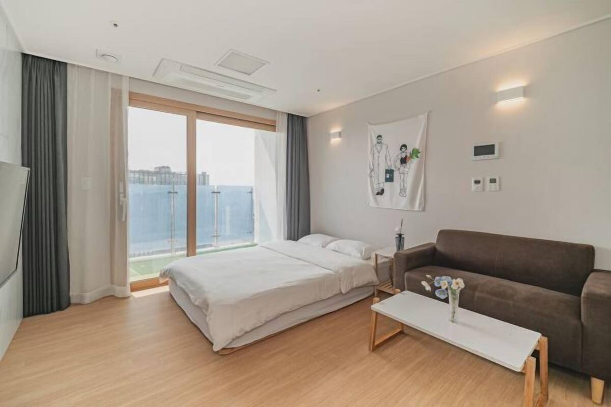 Une chambre d’hôtel moderne avec un grand lit, un canapé, une table basse et une vue sur la ville.