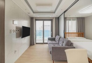 A modern hotel room with a sofa, bed, TV, and large windows. - Jeju The Terrace View (Jeju)