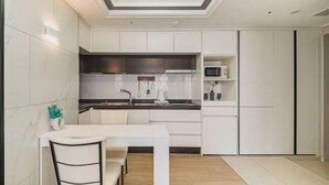 Une cuisine moderne avec des meubles blancs, une table à manger et une chaise noire.
