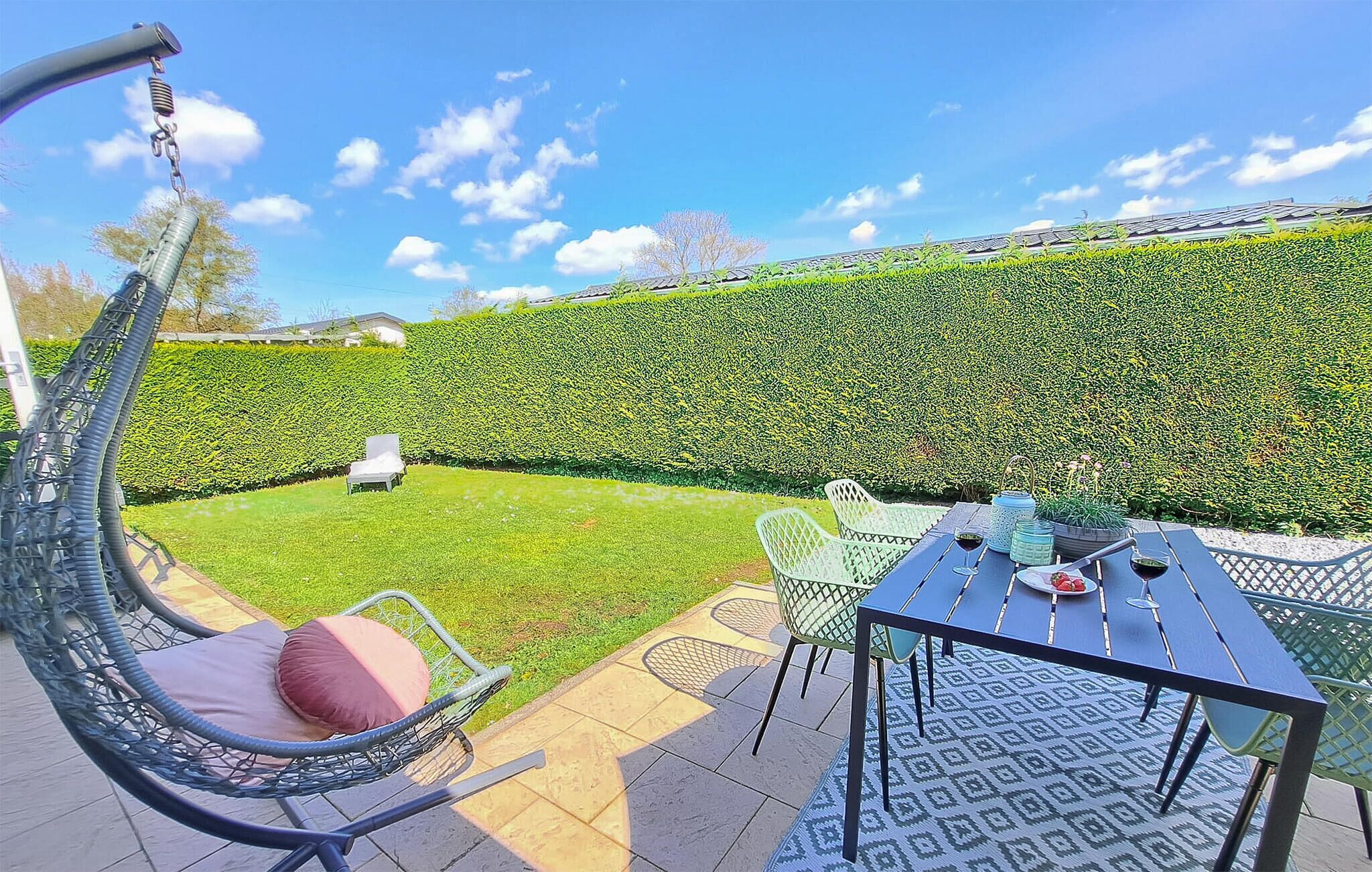 Eine Terrasse mit Tisch, Stühlen und einer Hängematte.
