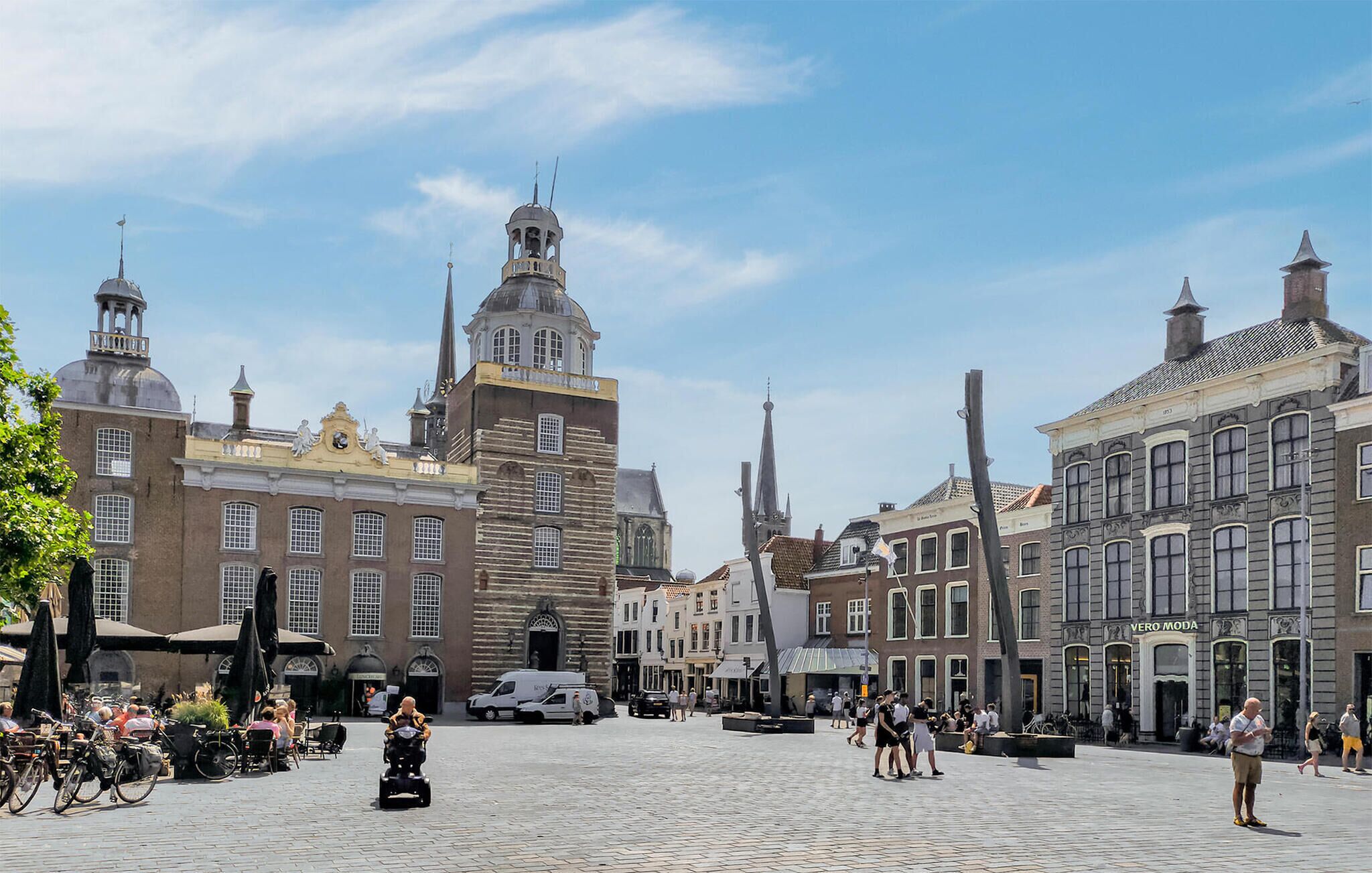 Une place historique aux pavés, d’architecture européenne traditionnelle, et sous un ciel dégagé.